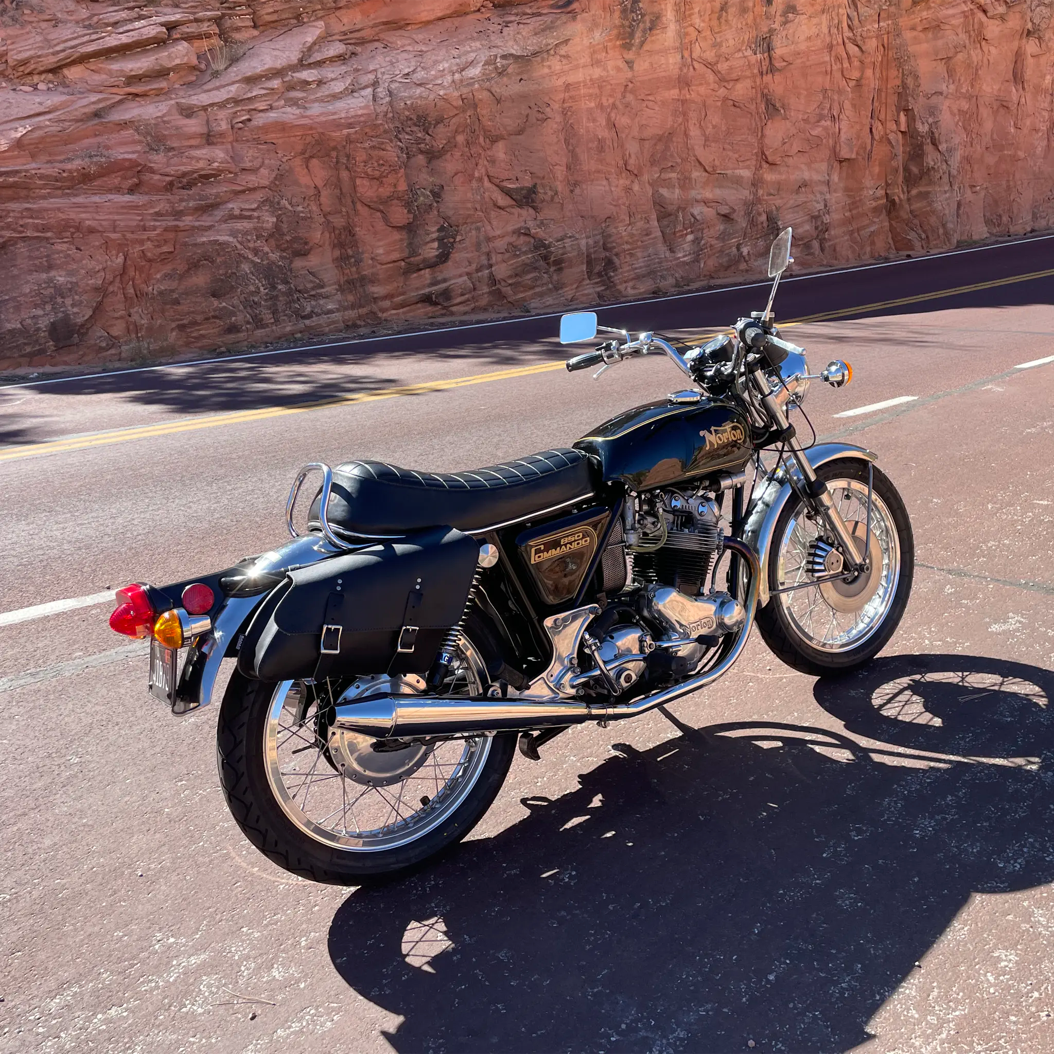 Black motorcycle parked on a road with a rocky wall in the background