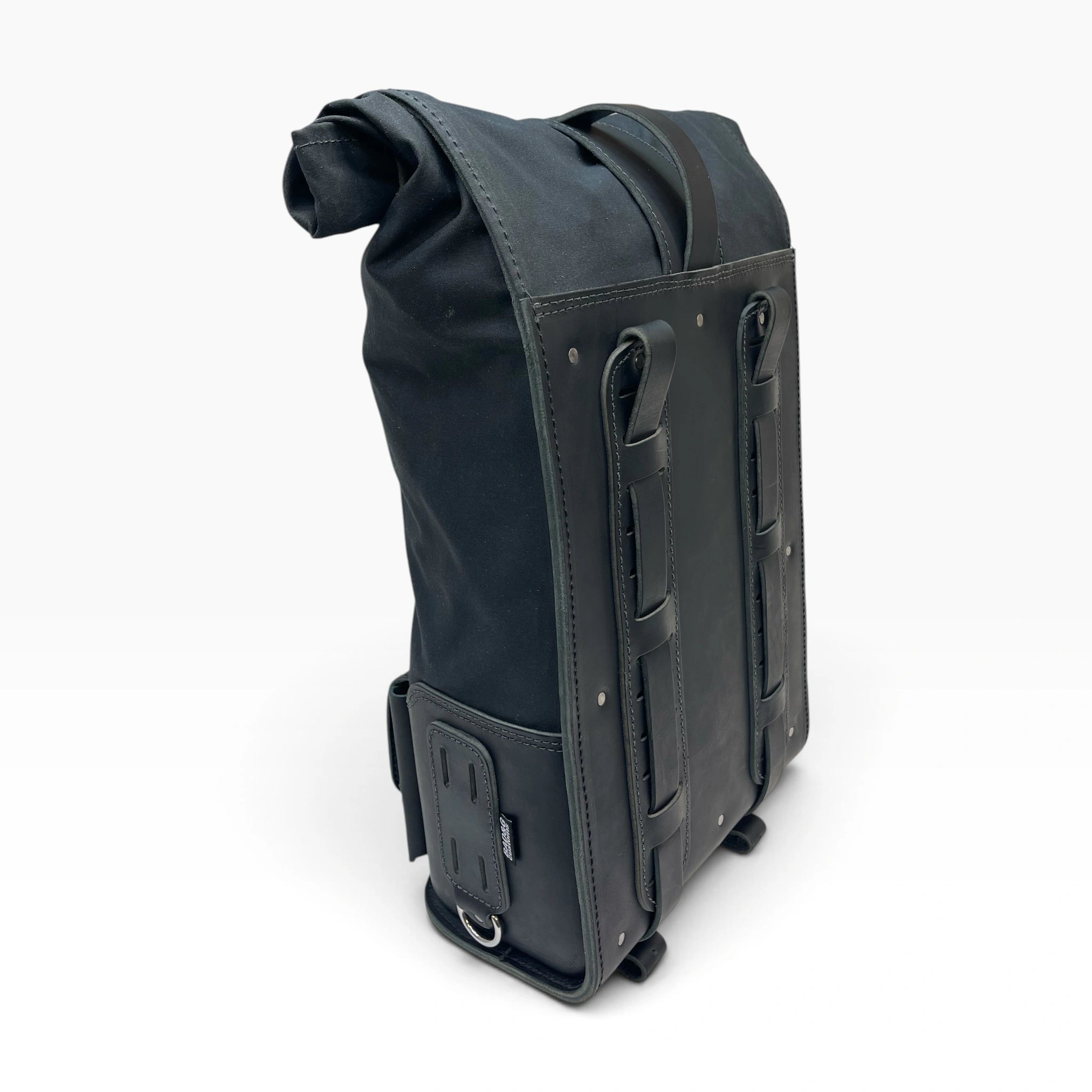 A black roll-top backpack with a weathered, distressed leather look, featuring dual vertical leather straps on the front, a side buckle attachment, and a top carry handle, shown on a white background.